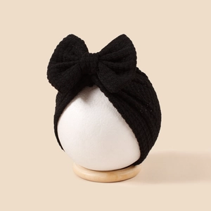Gros plan détaillé d'un turban en tricot noir pour bébé avec un grand nœud décoratif