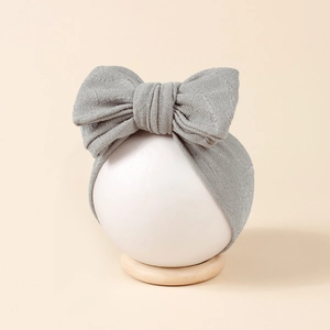 Détail d'un bandeau bébé avec grand nœud gris pailleté sur un mannequin d'affichage