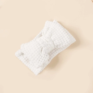 Detail of soft white crochet knitted baby headband featuring a large double bow design