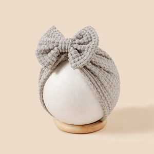 Texture tricotée en nid d'abeille d'un turban bébé gris avec un grand nœud décoratif