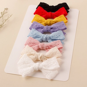 Detail view of eight embroidered lace bow hair clips in multiple colors for girls