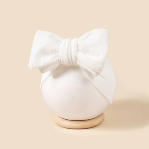 Vue détaillée d'un bandeau blanc à gros nœud en jacquard pour bébé sur support rond
