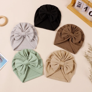 Flat lay of five ribbed knit baby turban hats with large bows in neutral earthy tones
