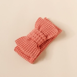 Detailed macro view of the soft coral pink knitted waffle texture on the baby headband bow
