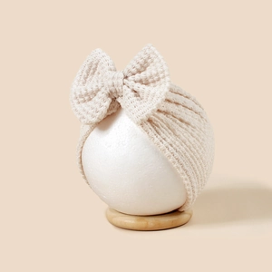Gros plan sur la texture gaufrée beige et le grand nœud d'un turban pour bébé
