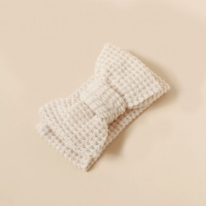 Close-up of beige knitted bow headband showing intricate texture and soft elastic fabric