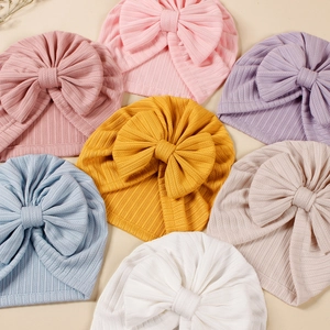 Close-up of multicolored ribbed knit baby turban hats with large decorative bows