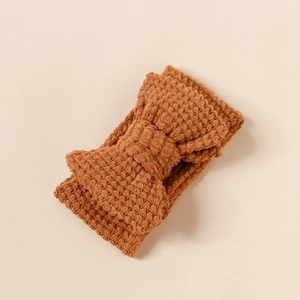 Detail of knit double-layered large bow headband for babies in ginger yellow textured yarn