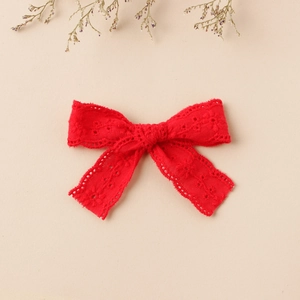 Detailed embroidery texture of a red lace bow clip with elegant floral patterns