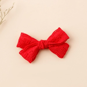 Detail of red hollow lace bow hair clip featuring fine floral embroidery texture