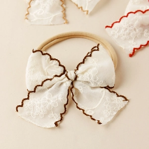 Détail macro du bandeau bébé en dentelle avec broderie marron ondulée et nylon élastique