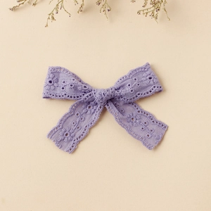 Detail of purple lace bow hair clip with intricate floral embroidery and handmade texture