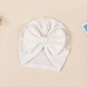 Close-up of white ribbed baby turban hat with a large decorative bow and soft texture