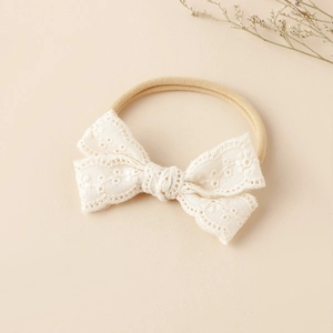 Detailansicht eines cremefarbenen Baby-Stirnbands aus Spitze mit floraler Stickerei