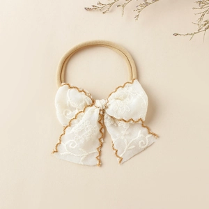 Détail du bandeau en dentelle pour bébé avec broderie dorée et ruban en nylon élastique