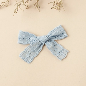 Close-up of light blue lace bow hair clip with floral embroidery and hollow details