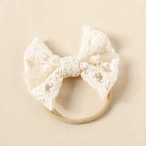Close-up of white floral embroidered lace bow on high elasticity nude nylon baby headband