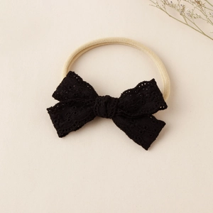 Detail eines schwarzen Spitzen-Stirnbands mit beigem, hochelastischem Nylonband für Babys