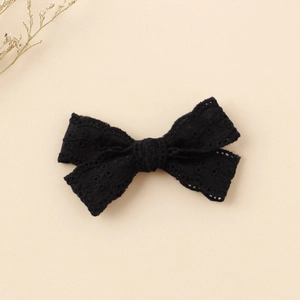Close-up of black lace bow hair clip showing intricate hollow embroidery and texture