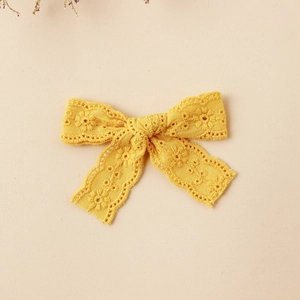 Detail of yellow lace embroidered bow hair clip with intricate floral patterns