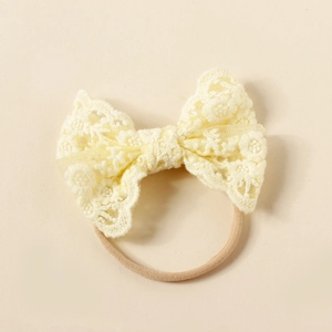 Detail of baby lace bow headband featuring delicate floral embroidery and elastic nylon band