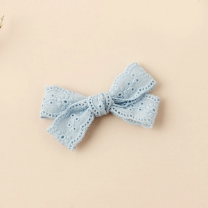 Close-up of light blue lace bow hair clip with detailed floral embroidery and openwork fabric