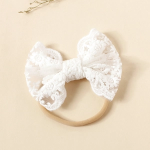 Close-up of white lace bow headband with floral embroidery and soft nylon band
