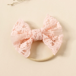 Detailed close-up of pink embroidered lace bow baby headband with soft nylon band