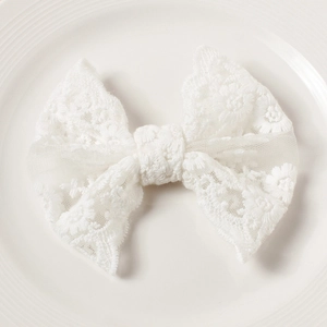 Close-up of white lace bow with delicate floral embroidery and scalloped edges