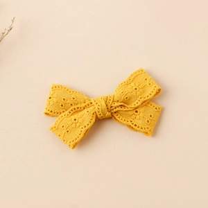Macro shot of bright yellow embroidered bow hair clip with hollow lace cotton texture