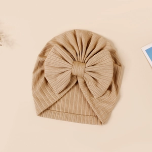 Detail of baby ribbed knit turban hat with large bow in a warm beige solid color
