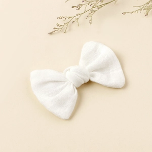 Detail of white fabric bow hair clip featuring soft cotton linen texture and minimalist design