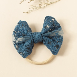 Detailed close-up of navy blue lace bow with floral embroidery on soft nylon baby headband