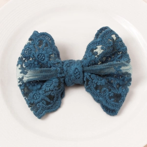Detailed view of a navy blue lace butterfly hair clip with floral embroidery on ceramic tray