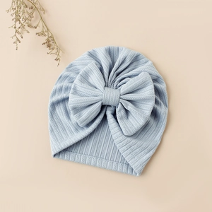 Detail of baby light blue jacquard knit beanie with an oversized bow on soft fabric