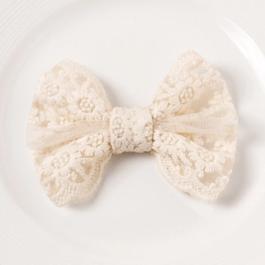 Close-up detail of cream lace bow hair clip with intricate floral crochet patterns