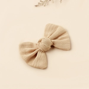 Detail of light beige ribbed fabric bow hair clip with natural floral decor on background