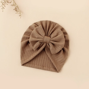 Detailed view of brown baby turban hat featuring a large bow and ribbed knit texture