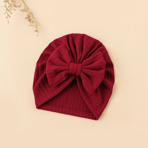 Detailed close-up of dark red ribbed knit baby beanie with large bow decoration