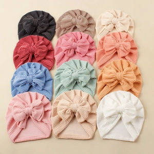 Flat lay of 12 colorful striped baby turban hats with large bows in soft knit fabric