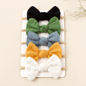 Detail view of five assorted color nylon headbands with textured bow knots on a white card