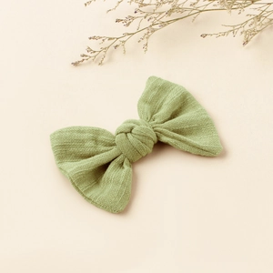 Detail of light green linen bow hair clip with textured fabric and central knot