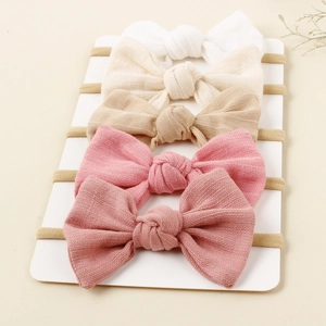 Close-up of five colorful soft fabric baby bow headbands on white cardboard display