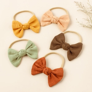 Set of five soft nylon baby headbands with muslin cotton bows in various warm colors
