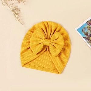 Close-up of mustard yellow baby beanie with ribbed knit texture and oversized bow detail