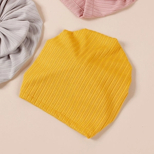 Detailed texture of ribbed knit baby beanies in yellow, grey and pink colors