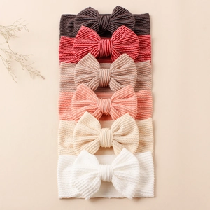 Détail de six bandeaux pour bébé en tissu côtelé avec nœuds en gris, rose et beige