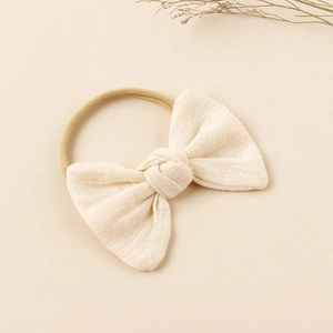 Detail of a creamy beige linen bow headband showing high-elastic nylon and fabric texture