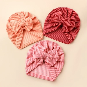 Detailed view of three striped knit baby turbans with large bows in varied colors
