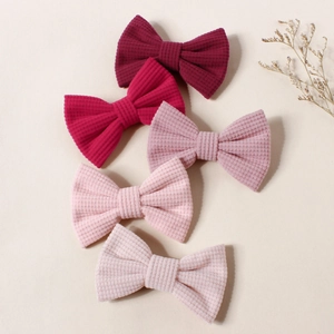 Détail montrant cinq barrettes à nœuds texturés à rayures de couleurs variées pour filles